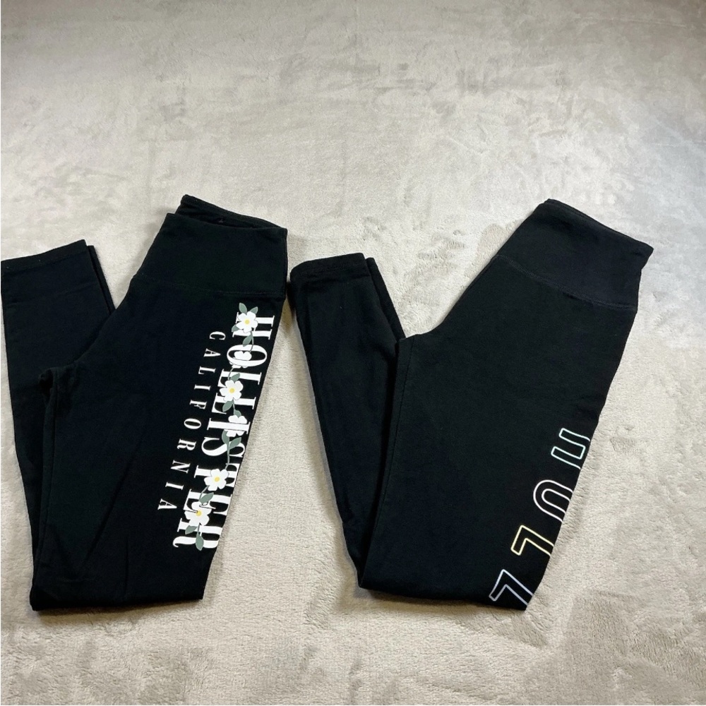 A set of two Hollister Black Leggings with White Daisy & Logo Side Prints